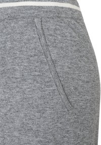 Graue Baumwoll-Jogginghose mit weiß gestreiftem Taillenbund, strukturiertem Stoff und seitlichen Taschen für zusätzliche Funktionalität.