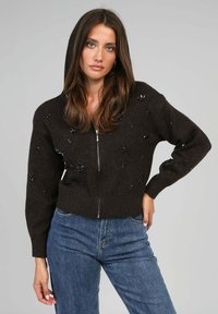 Pull à capuche marron, avec fermeture éclair à l'avant, agrémenté de décorations. Ourlets et poignets côtelés, fabriqué en tissu doux, adapté pour un porter décontracté.