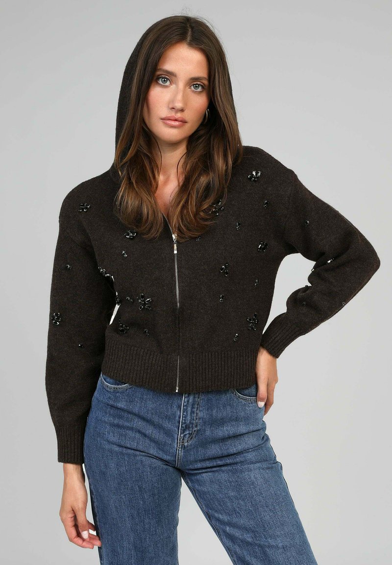 Pull à capuche marron, avec fermeture éclair à l'avant, agrémenté de décorations. Ourlets et poignets côtelés, fabriqué en tissu doux, adapté pour un porter décontracté.