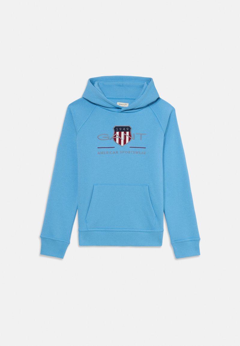 Moletão azul claro feito de tecido misto de algodão. Apresenta um bolso canguru na frente, punhos canelados e um emblema com riscas vermelhas e azuis marinho.