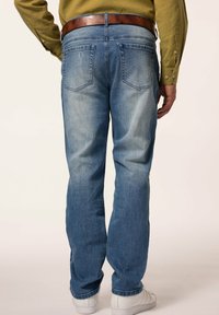 Jeans de denim azul claro con corte recto, que presentan dos bolsillos traseros y un cinturón de cuero marrón. Textura suave y acabado desgastado.