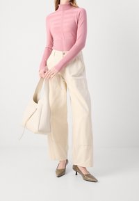 Light pink turtleneck top with horizontal stripes, cream wide-leg pants, metallic brown pointed-toe heels, and a beige tote bag.