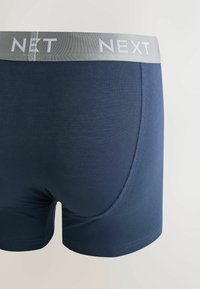 Boxer in cotone blu navy con fascia elastica grigia sulla vita con la scritta "NEXT" in bianco. Texture liscia e design aderente.