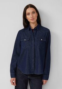 Dunkelblaues Denimhemd mit Kragen, langen Ärmeln und zwei Brusttaschen. Mit Druckknöpfen und einem leicht abgerundeten Saum. Weicher Stoff.