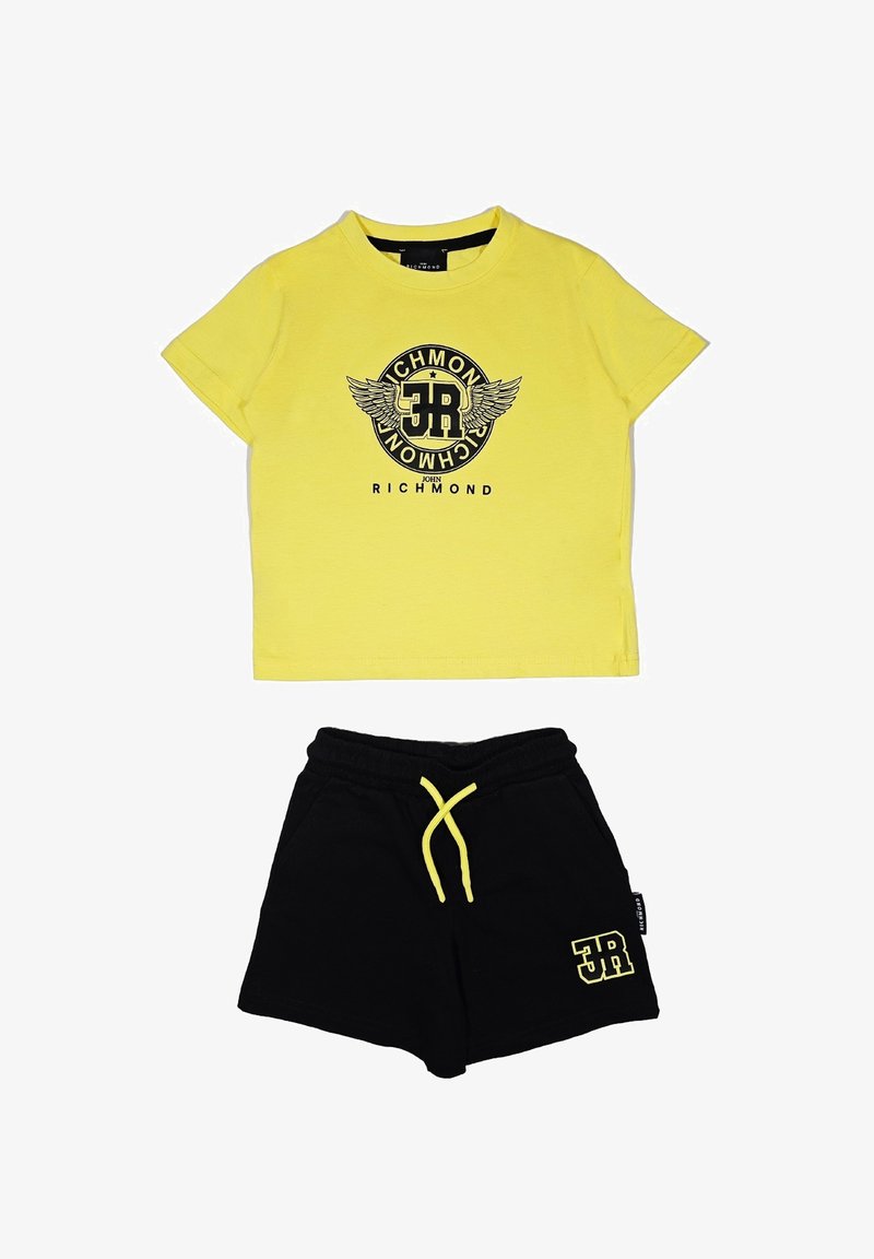 T-shirt giallo in cotone a maniche corte con un logo nero e un grafica di ali; abbinato a pantaloni corti neri con una coulisse gialla e logo.