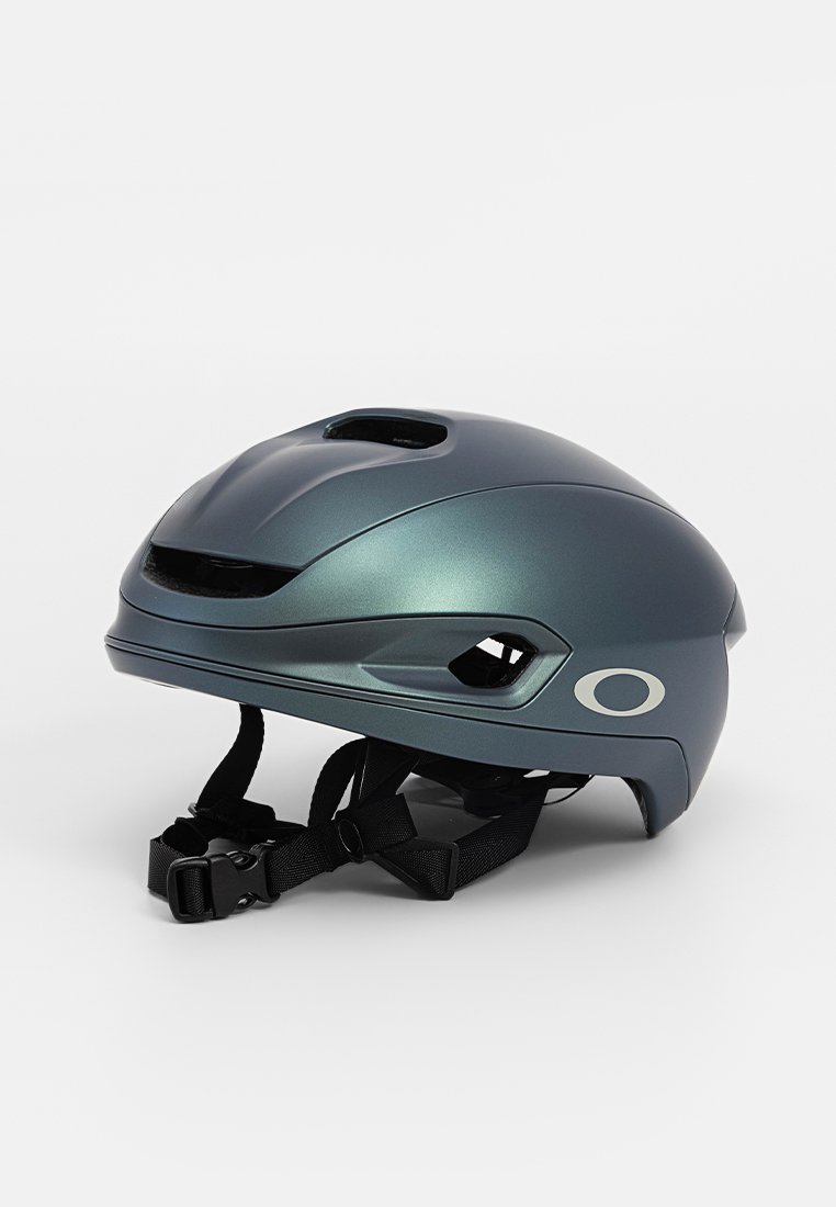 Snygg metallisk mörkgrå cykelhjälm med ventilationshål, justerbar svart hakrem och ovalt logotyp på sidan.