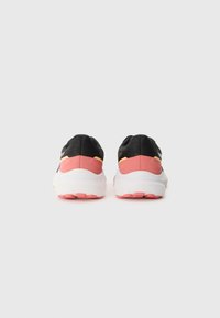 Des chaussures de sport noires avec des accents roses, un dessus texturé, un col rembourré et une semelle intermédiaire blanche comportant une semelle extérieure rose à motif.