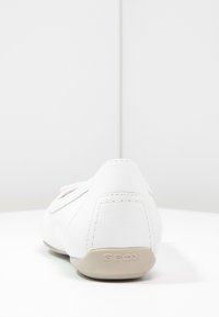 Vit lädersko med en slät yta, rund form och subtila sömnadsdetaljer. Har en ljusfärgad sula och GEOX-logotyp.
