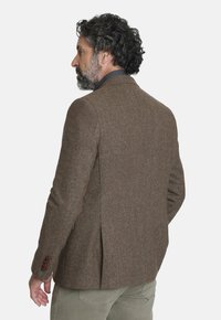 Blazer de lana texturizado marrón con cuello de muesca, una abertura en la parte trasera y acentos en botones marrones, visto desde la parte de atrás.