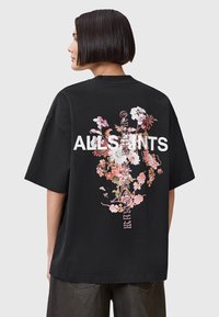 T-shirt nera a maniche corte con un design floreale colorato e il testo "ALLSAINTS" in evidenza sulla schiena.