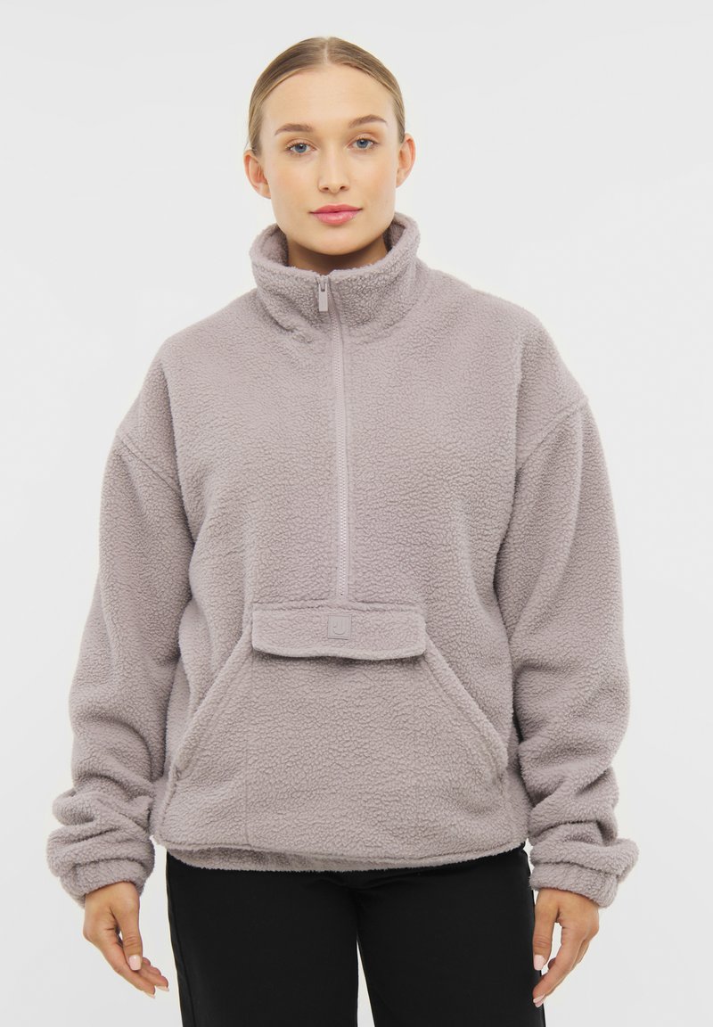 Pullover in pile di colore grigio chiaro, con colletto alto e chiusura a mezzo zip. Comprende una tasca frontale e un tessuto morbido e testurizzato.