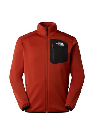 Giacca in pile rossa con colletto alto, tasca sul petto con cerniera nera e tasche laterali con zip. Presenta polsini elasticizzati e una texture liscia.