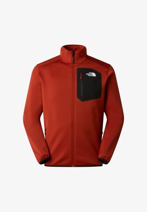 Giacca in pile rossa con colletto alto, tasca sul petto con cerniera nera e tasche laterali con zip. Presenta polsini elasticizzati e una texture liscia.