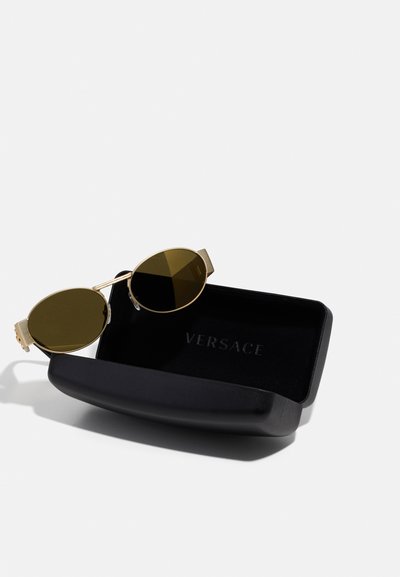 Kuldtoonilised ümmargused prillid tumeroheliste objektiividega, paigutatud musta Versace kõvakatta. Katta peal on reljeefne logo.