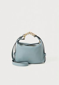 Lyseblå lædertaske med rundet design, guldfarvet beslag, aftagelig skulderrem og lynlås lukning. Har et minimalistisk logo.