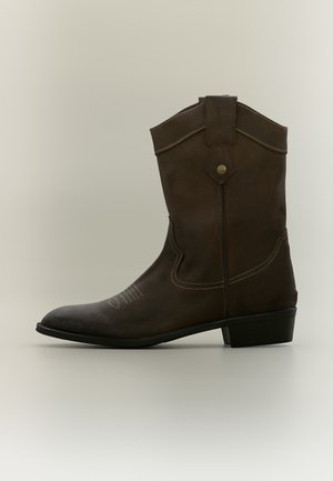 Bota de vaquero de cuero marrón hasta la mitad de la pantorrilla con costuras decorativas, lengüeta para tirar y tacón bajo apilado sobre un fondo neutro.