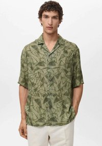 Camisa verde de manga corta con un patrón geométrico de hojas, hecha de una tela ligera, con un cierre delantero de botones y un corte relajado.