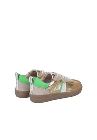 Sneakers con una toma metallica dorata, dettagli in suede verde, lacci bianchi e una suola in gomma marrone testurizzata. Design contemporaneo con materiali misti.