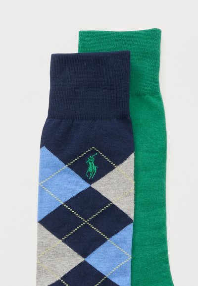 Δύο διπλωμένες κάλτσες δίπλα η μία στην άλλη, μία πράσινη και μία ναυτικού μπλε με μπλε, γκρι και ανοιχτό πράσινο σχέδιο argyle και ένα μικρό πράσινο κεντημένο λογότυπο.