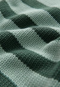 Nertinė medžiaga, pasižyminti pakaitomis tamsiai žaliais ir šviesiai mėtų geometriniais raštais. Tekstūra atrodo minkšta, matomi siuvimo detalės.