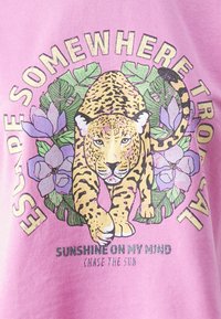 Un leopardo caminando hacia adelante, rodeado de hojas verdes y flores moradas sobre un fondo rosa, con texto sobre escapadas tropicales y sol brillante.