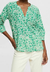 Blusa verde a fantasia floreale con scollo a V, maniche tre quarti e vestibilità rilassata, realizzata in tessuto leggero.