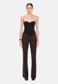 Czarny strapless bodysuit o strukturalnym kroju w połączeniu z brązowymi spodniami z zamszu o wysokim stanie, z przodem na sznurki i rozszerzanym fasonem.