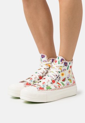 Wysokie sneakerzy wykonane z białego płótna z kolorowymi kwiatowymi i owocowymi wzorami, białymi sznurówkami oraz teksturowanymi gumowymi podeszwami.
