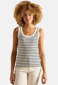 White striped tank top featuring navy vertical stripes, a rounded neckline, and wide shoulder straps, paired with light-colored pants.