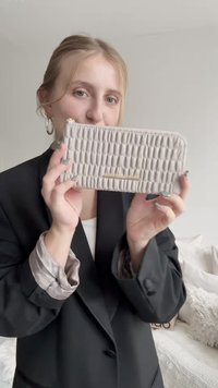 Ανοιχτό γκρι πορτοφόλι με ραφή, λεπτό ορθογώνιο σχήμα, κλείσιμο με φερμουάρ και χρυσή μεταλλική λεπτομέρεια.