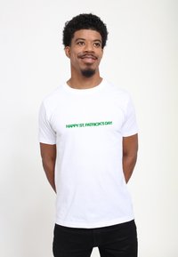 White cotton t-shirt featuring green text that reads "HAPPY ST. PATRICK'S DAY!" The shirt has a round neckline and short sleeves.