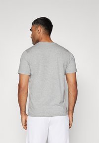 Grå bomulds T-shirt med korte ærmer og rund halsudskæring, vist fra ryggen, med en blød tekstur og afslappet pasform.