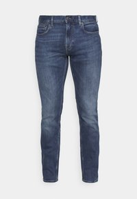Jeans de mezclilla azul oscuro, con corte recto, cinco bolsillos, cierre de botón y ligeras áreas desgastadas en la parte delantera.