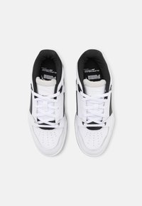 Hvite lær-sneakers med svarte detaljer, snøring, perforert tåboks og logo på tungen. Polstret krage for komfort.
