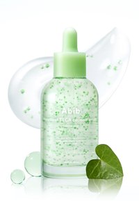 Klare Flasche des Abib Heartleaf TECA Kapsel-Serums mit grünem Tropfer, grünen Kapseln im Inneren, glattem Serumstrich und herzförmigem Blatt.