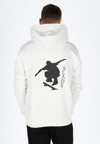 Felpa bianca con grafica silhouette di un skateboarder nero sulla schiena, accompagnata dalla parola "SLADE", e polsini e orlo a costine.