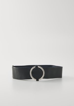 Ceinture large noire en matériau texturé avec une boucle double anneau argentée posée à plat sur une surface blanche.