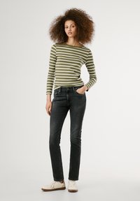 Svītraina zaļa gara piedurkne augšdaļa apvienota ar tumšo zilo šauru džinsu un baltajām kedām. Augšdaļa ir ar horizontālām svītrām un apaļu kakla izgriezumu.