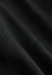 Czarna bawełniana tkanina o gładkiej teksturze, z diagonalnymi zagięciami i subtelnymi wzorami splotu na całej powierzchni.