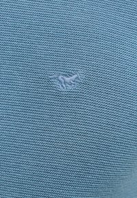Maglione lavorato a maglia di colore blu chiaro con un motivo testurizzato e un piccolo logo di un cavallo ricamato al centro.