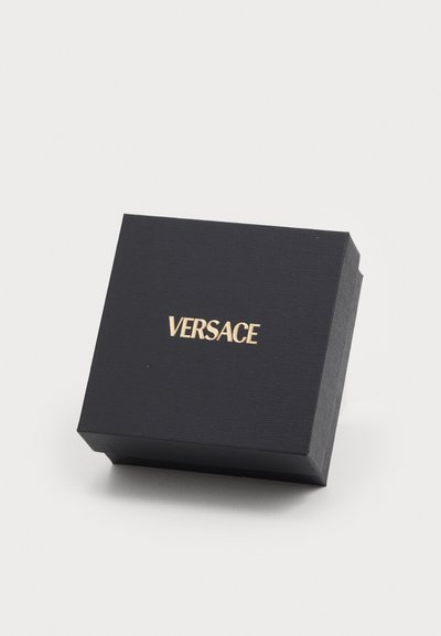 Zwarte rechthoekige geschenkdoos met een gestructureerd oppervlak. Gouden "VERSACE" logo prominent weergegeven op de bovenkant. Minimalistisch ontwerp.