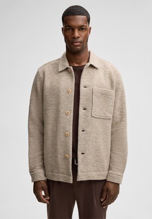 Beige wool shirt jacket with a collar, button front, and one chest pocket. Smooth texture with wooden buttons and a relaxed fit.