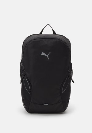 Sac à dos noir Puma avec poche zippée à l'avant, poches latérales en mesh, poignée supérieure et logo Puma réfléchissant sur le panneau avant.