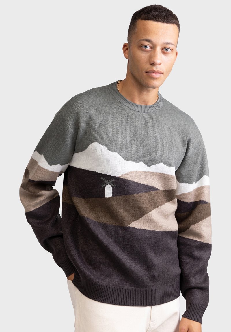 Knit sweater featuring a mountain landscape pattern in gray, tan, and dark colors, round neckline, and ribbed cuffs and hem.