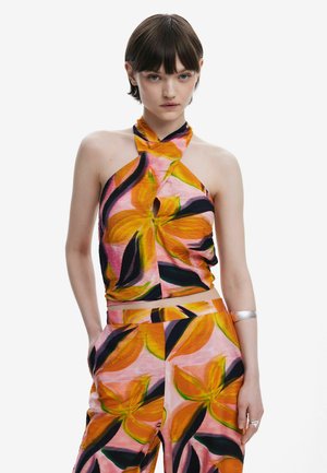 Top a halter colorato e pantaloni abbinati in un motivo floreale con fiori arancioni e rosa e accenti verdi su uno sfondo chiaro.