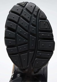 Gumová podrážka s texturovaným povrchem obsahující obdélníkové a kruhové vzory pro lepší přilnavost, převážně černá s některými světlými akcenty.