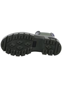 Suela de goma verde con surcos profundos y patrones de diamante. Presenta una correa segura y bordes reforzados para mayor durabilidad.