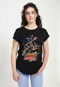 Černé bavlněné tričko s barevným potiskem "Star Wars", zobrazuje postavy a lodě na pozadí vesmíru, s ohrnutými rukávy.