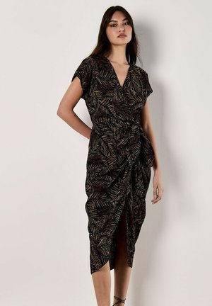 Black knee-length wrap dress featuring a leaf pattern in gold and rust tones, with short sleeves and a gathered waist detail.
