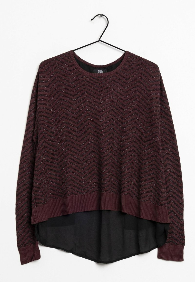 Pull marron avec un motif en zigzag, doté d'une couche inférieure noire transparente et de poignets et ourlet côtelés. Suspendu à un crochet noir.
